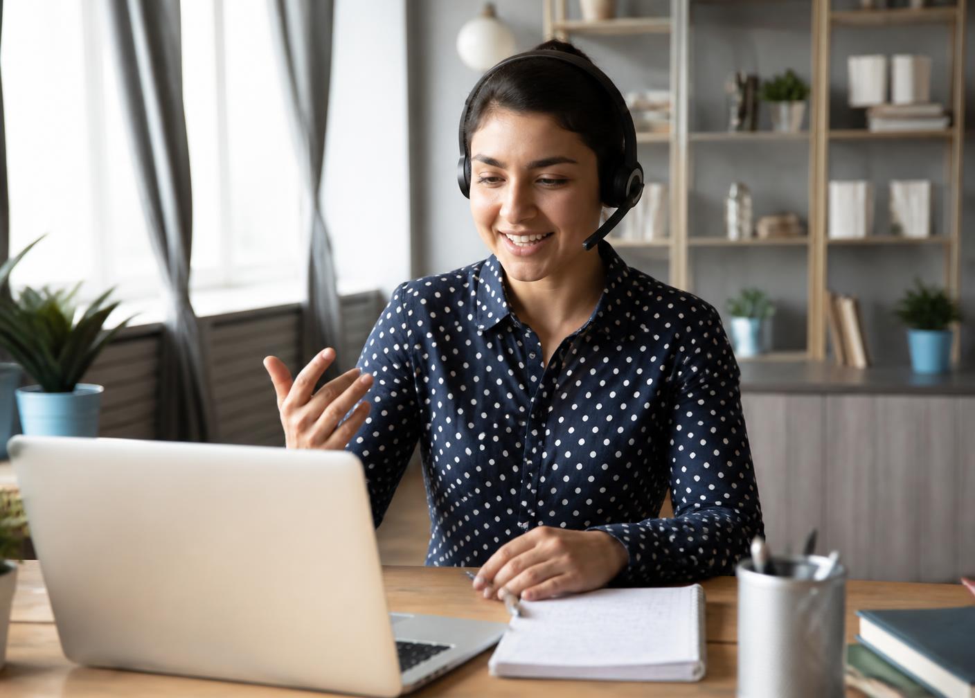 Trainer teaching an online AI class from a home desk with a laptop and headset