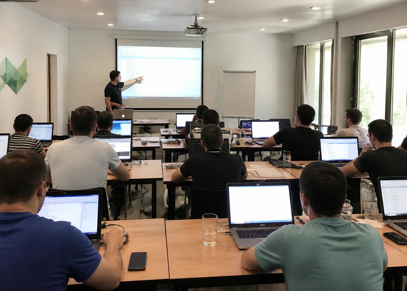 Students learning on laptops inside a physical computer training classroom